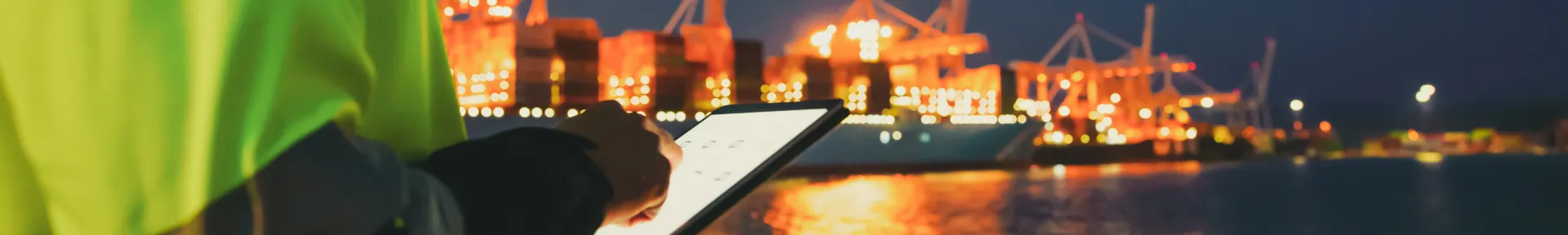 Man at a harbour on ipad at night
